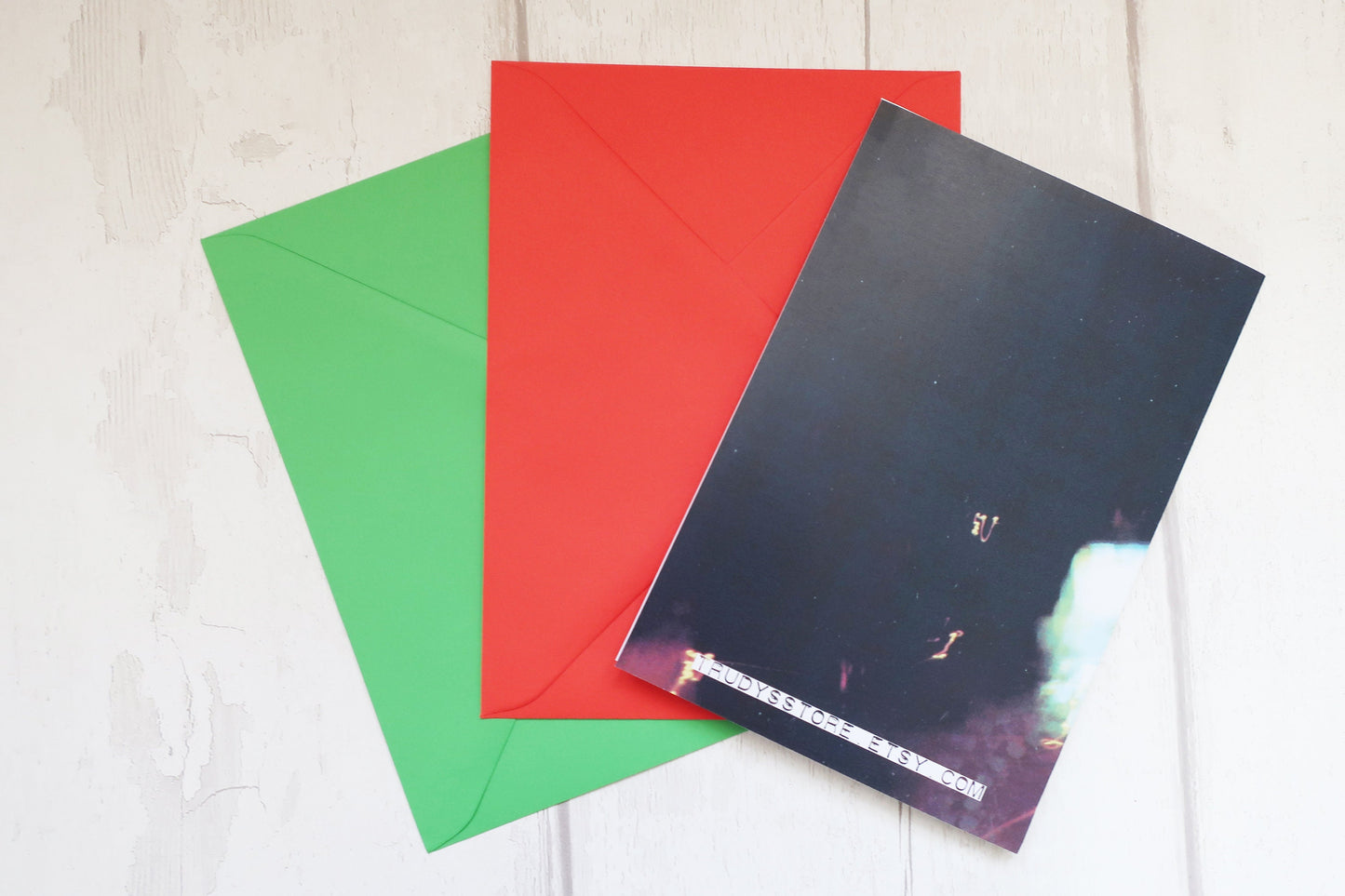 Three colorful envelopes (green, red, black) on a light wooden surface.