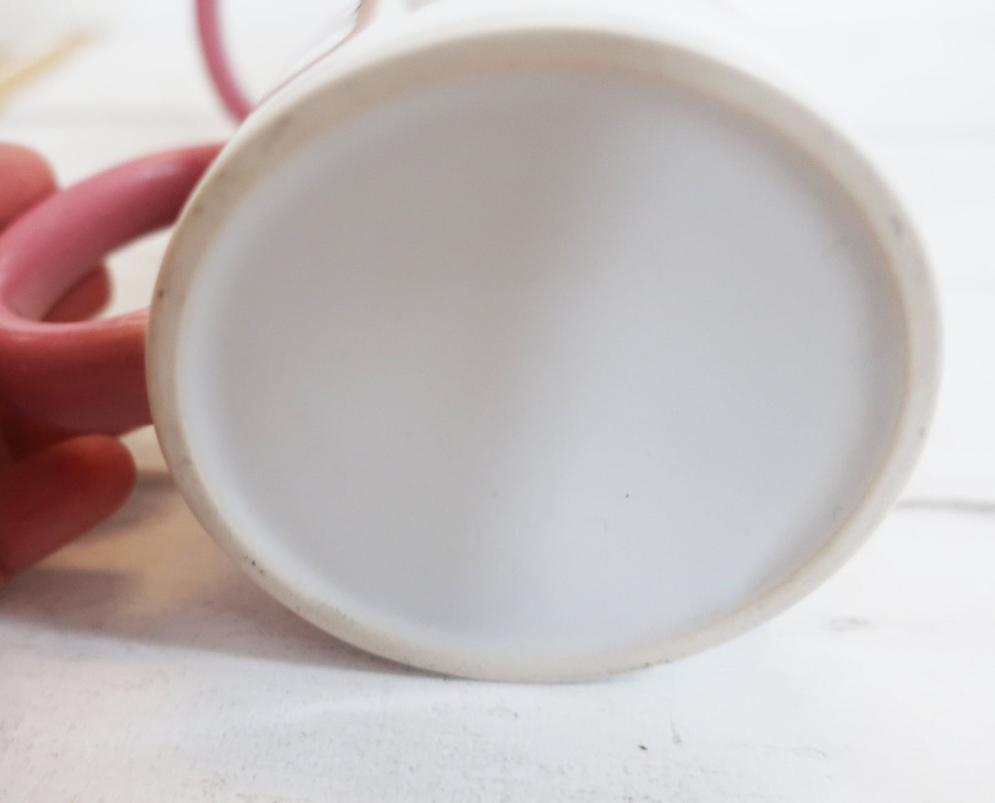 White mug with a pink handle on a white background