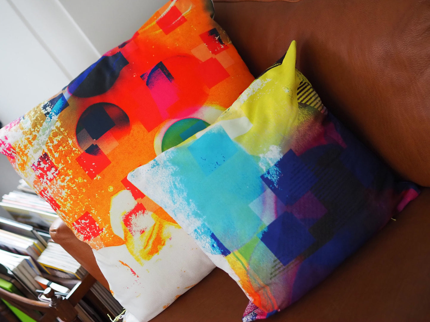 Two colorfulcushions on a chair with books in the background