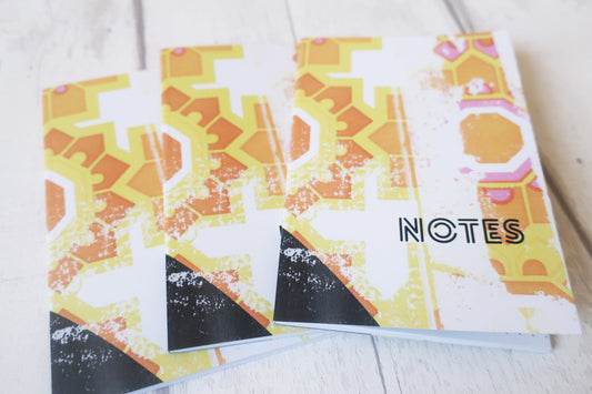 Three notebooks with geometric patterns and 'NOTES' text on a light background