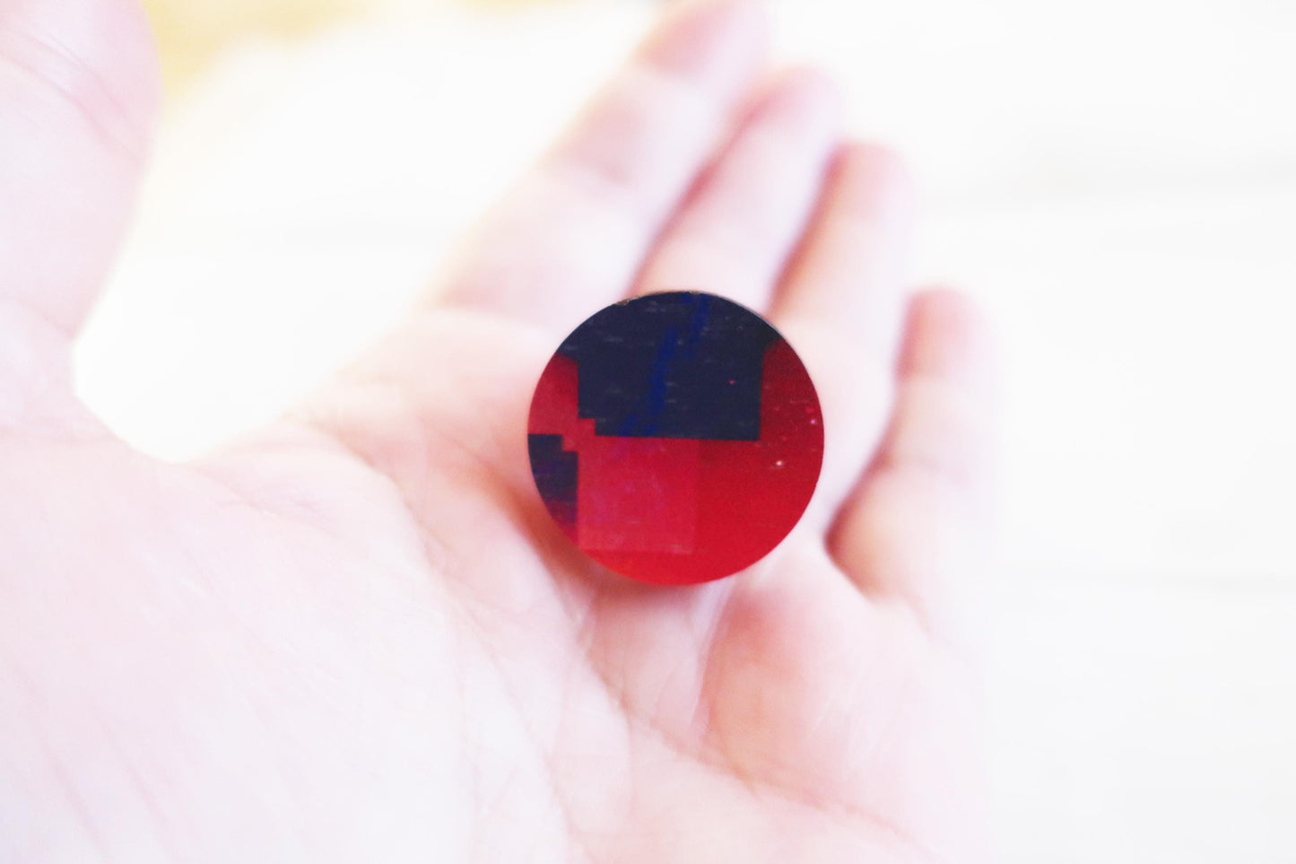 Round red and blue ring held in a hand against a blurred background
