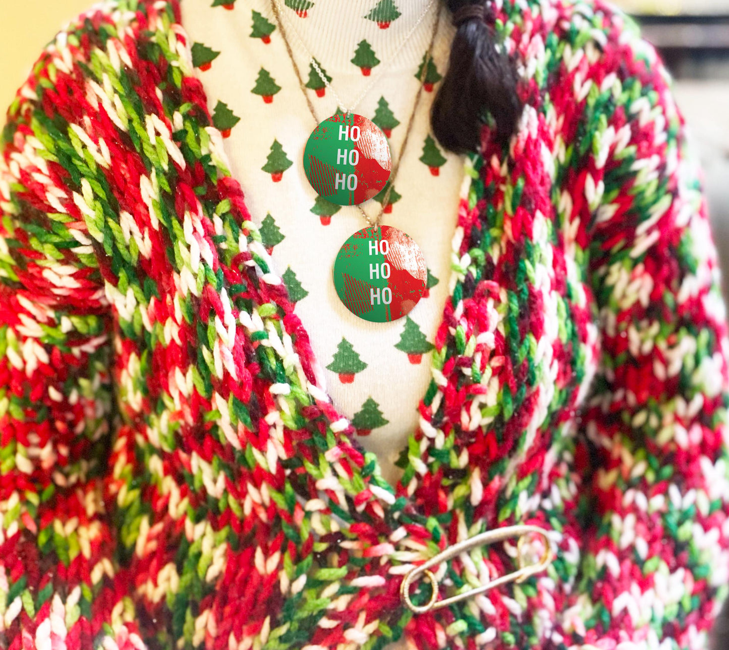 Red, green, and white striped cardigan with Christmas-themed necklaces on a mannequin.
