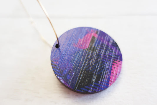 Round purple and pink earring on a white background