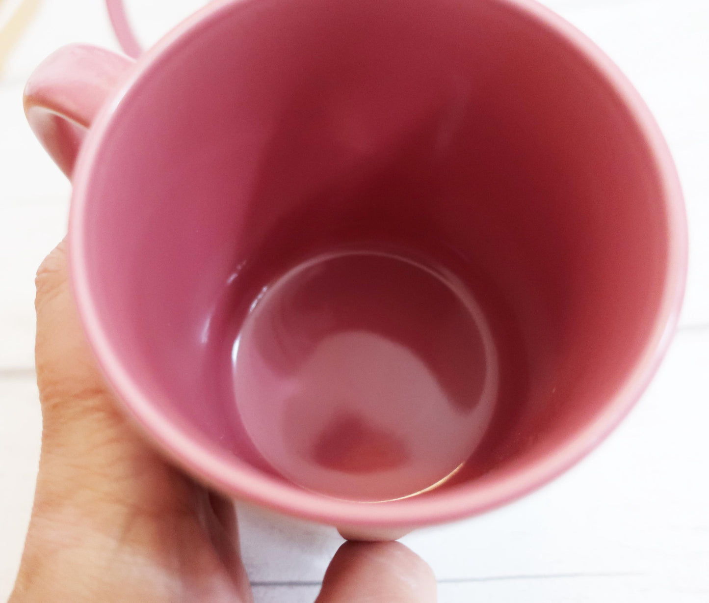 Pink mug held by a hand on a white background