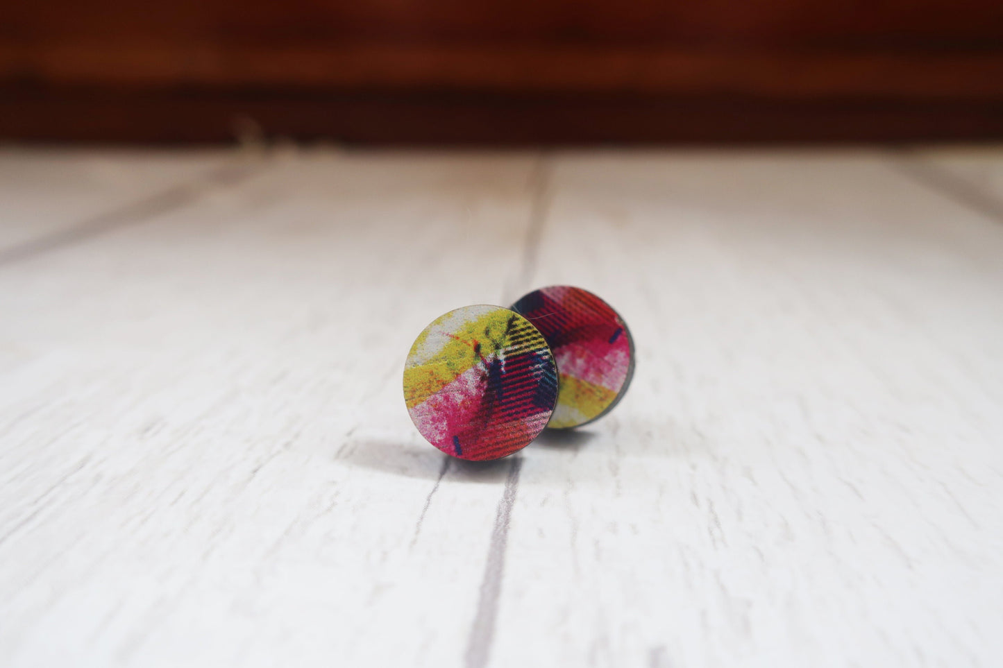 Colorful tie-dye patterned earrings on a white surface