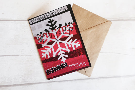 Christmas card with snowflake design and text 'I'm dreaming of a white Christmas' on a wooden surface.