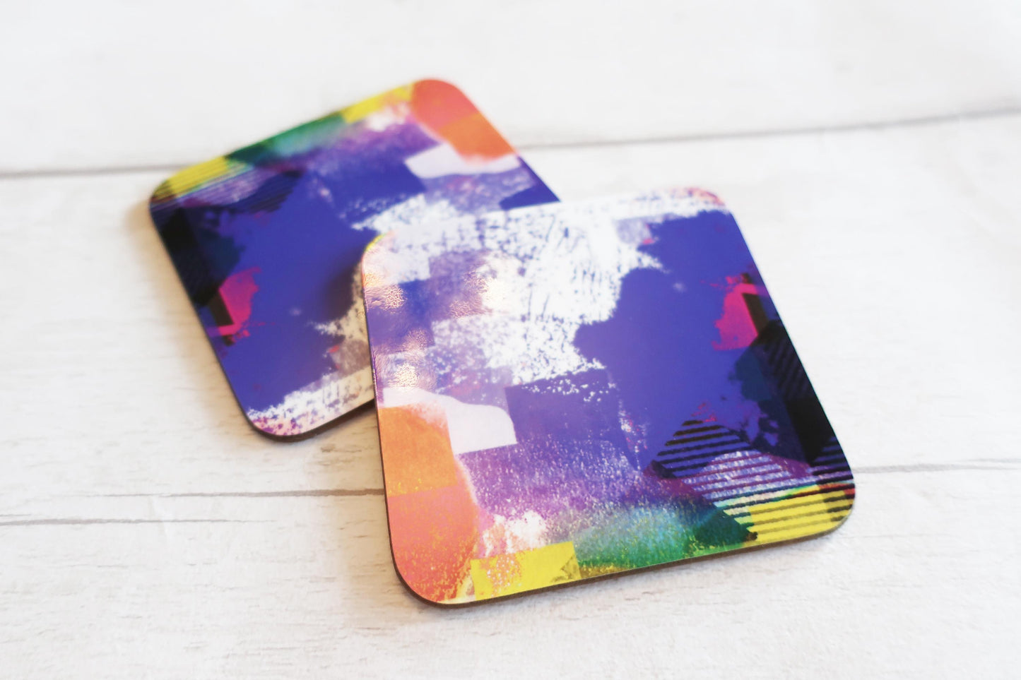 Two colorful coasters on a white wooden surface