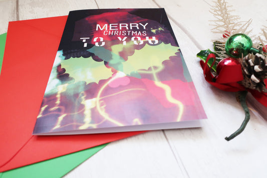 Colorful Christmas card with 'Merry Christmas to you' text on a white surface with festive decorations.