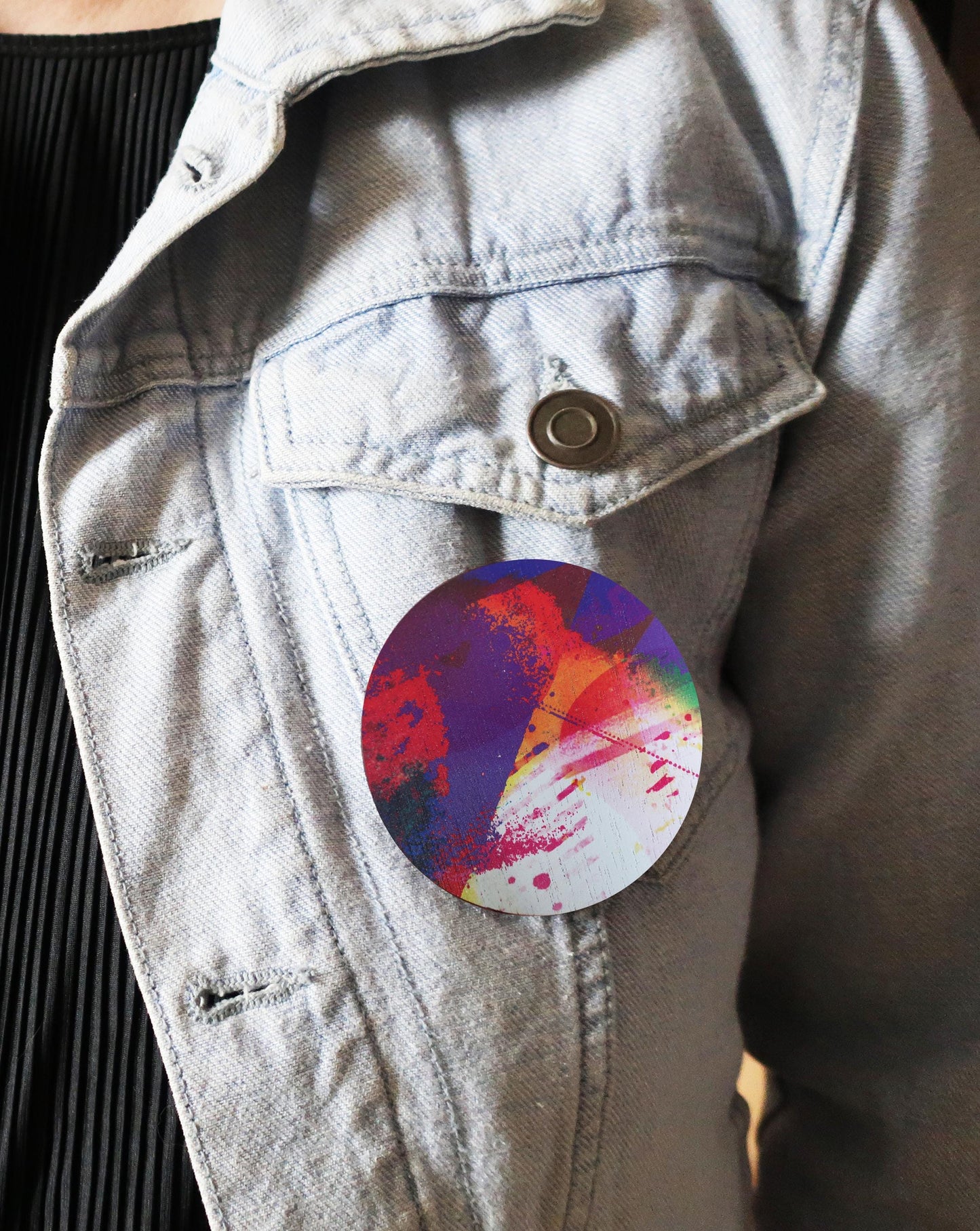 Colorful circular brooch attached to a light-colored jacket