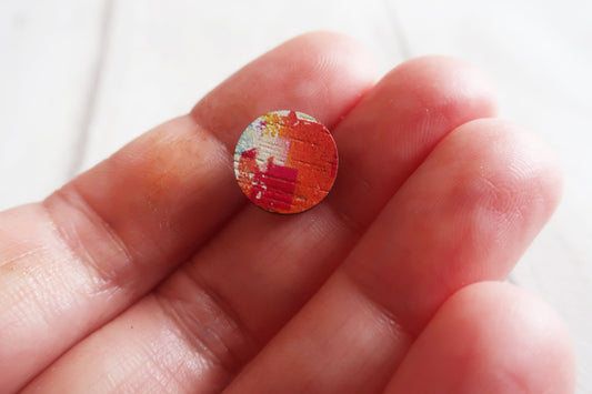 Small round object with a colorful pattern held between fingers against a white background