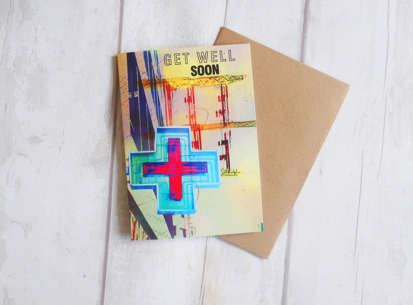 Get well soon card with colorful cross design on a wooden surface