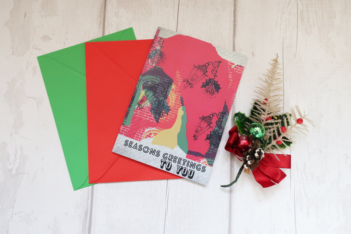 Christmas card with red envelope and decorative elements on a light wooden surface
