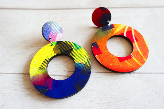 Colorful round earrings on a light wooden surface