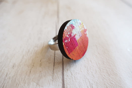 Ring with a colorful circular design on a light wooden surface