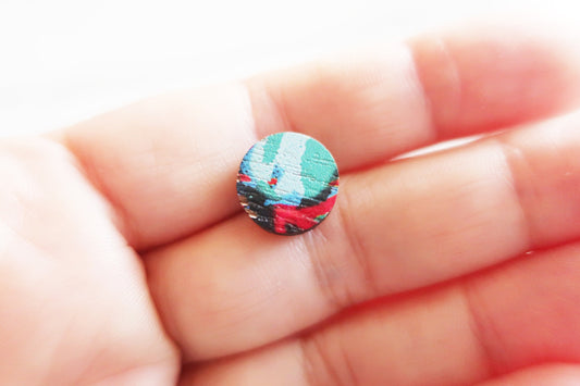 Colorful earring held between fingers on a light background