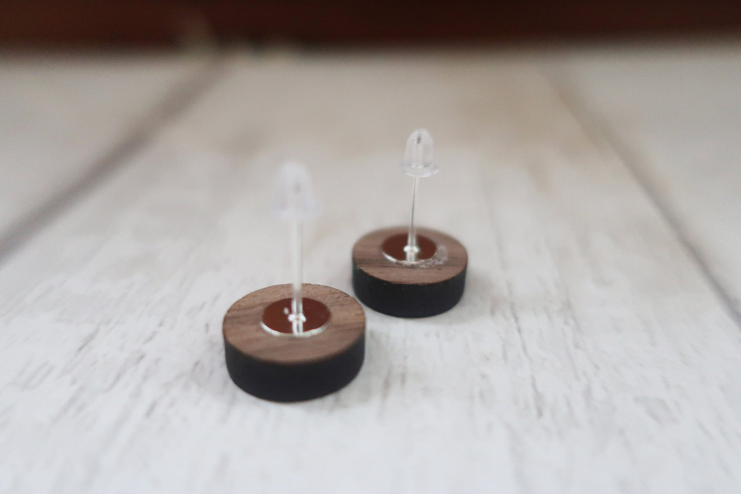 Wooden earrings on clear stands against a light wooden background