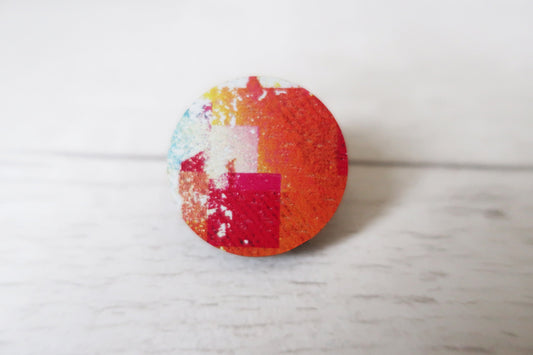 Colorful circular pin badge on a light wooden surface