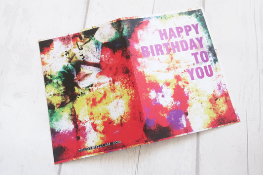 Colorful birthday card with abstract design and 'Happy Birthday To You' text on a white surface.