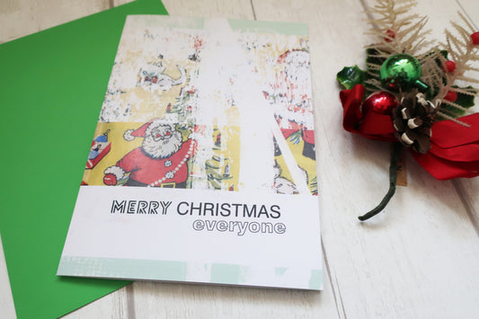 Christmas card with Santa Claus illustration and 'Merry Christmas everyone' text, placed on a green envelope