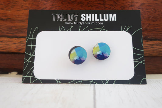 Colorful round earrings on a Trudy Shillum branded card against a wooden background