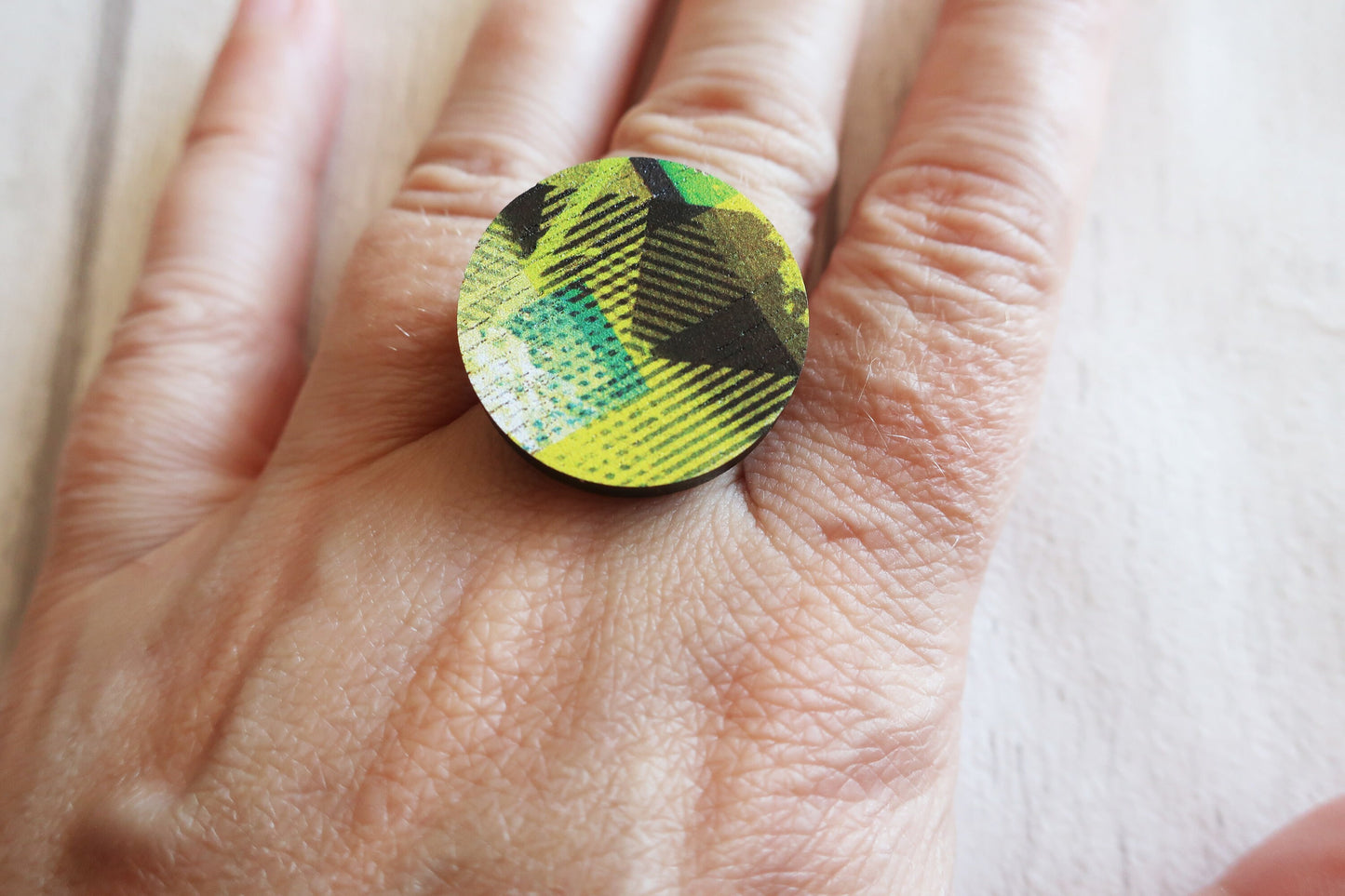 Close-up of a hand wearing a round, multicolored ring.
