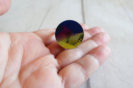 Hand holding a round, multicolored ring against a light background