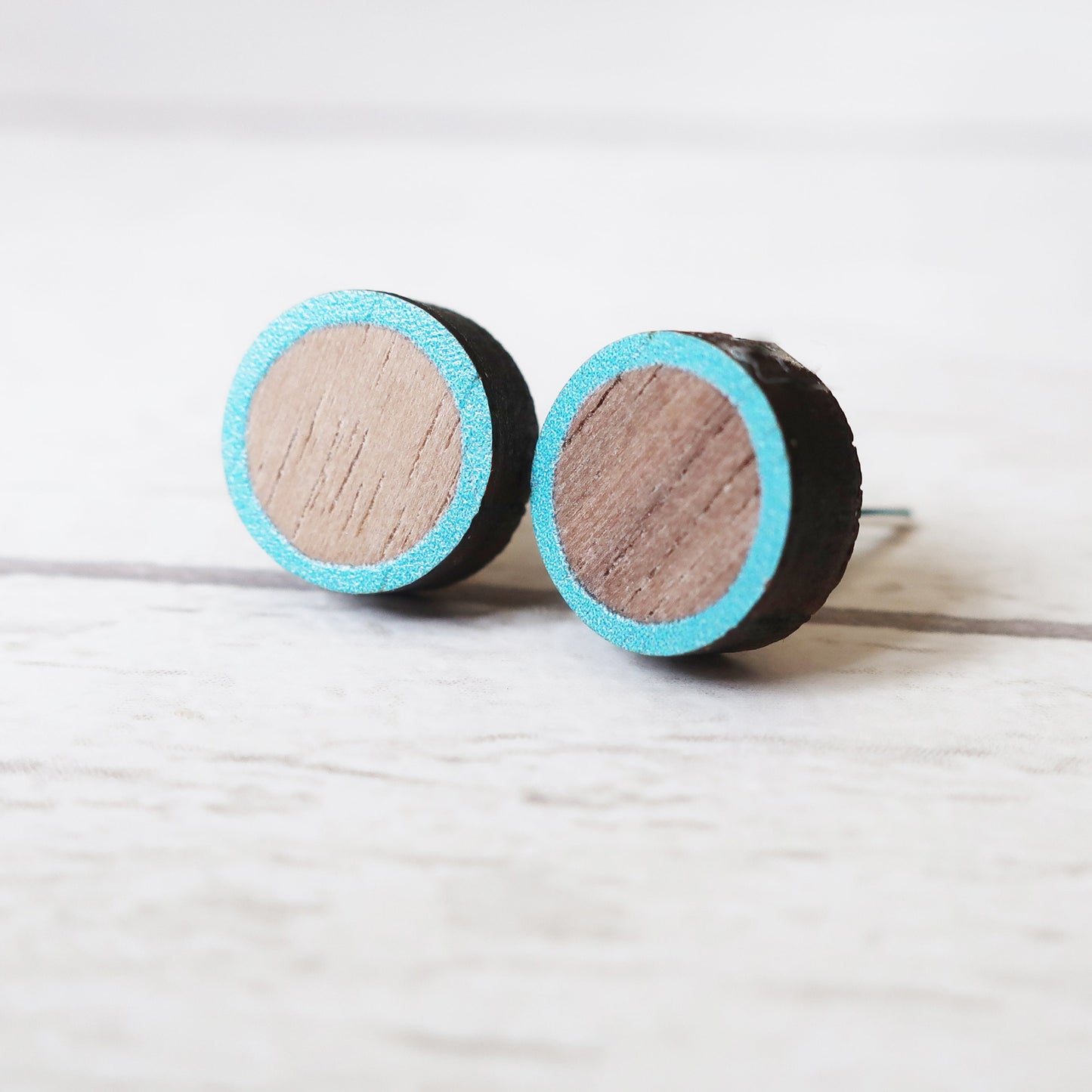 Round wooden earrings with turquoise rim on a light gray background