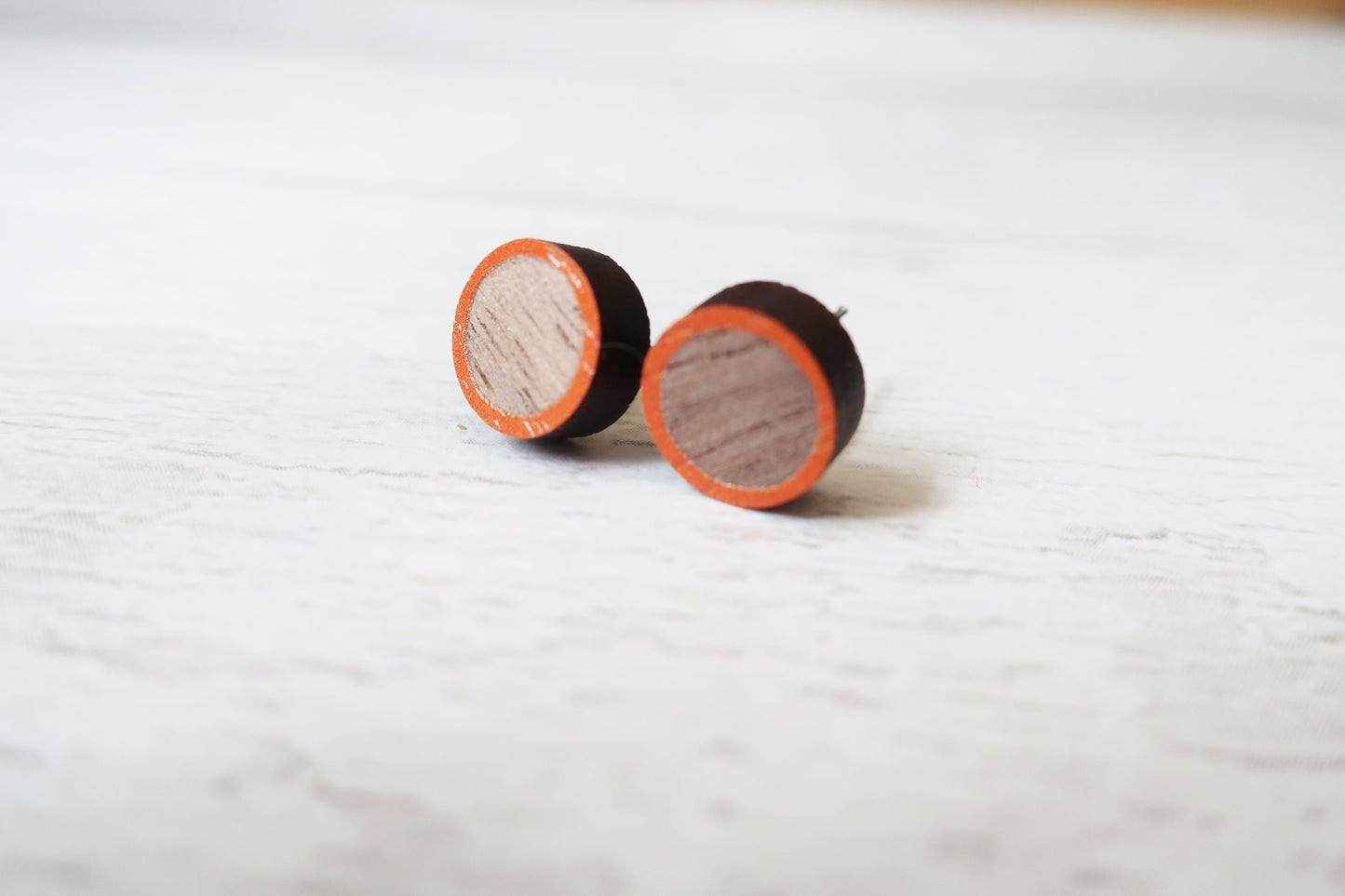 Round wooden earrings with orange accents on a light gray background
