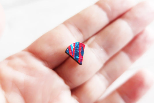 Colorful geometric earring on a finger against a blurred background