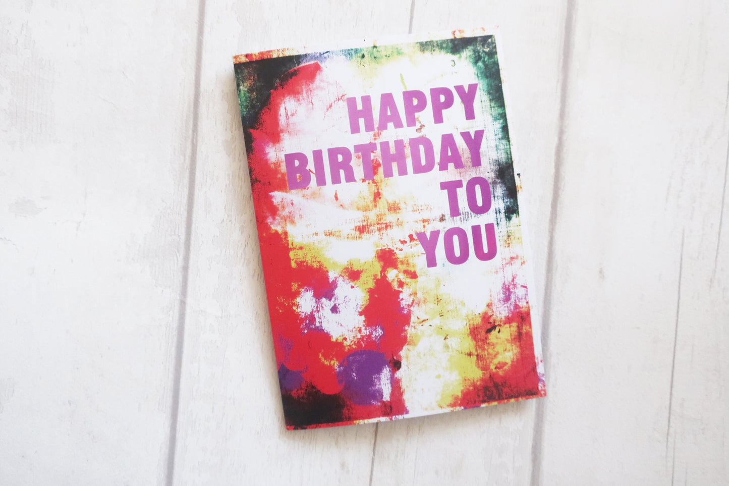 Colorful birthday card with 'Happy Birthday To You' text on a white wooden surface