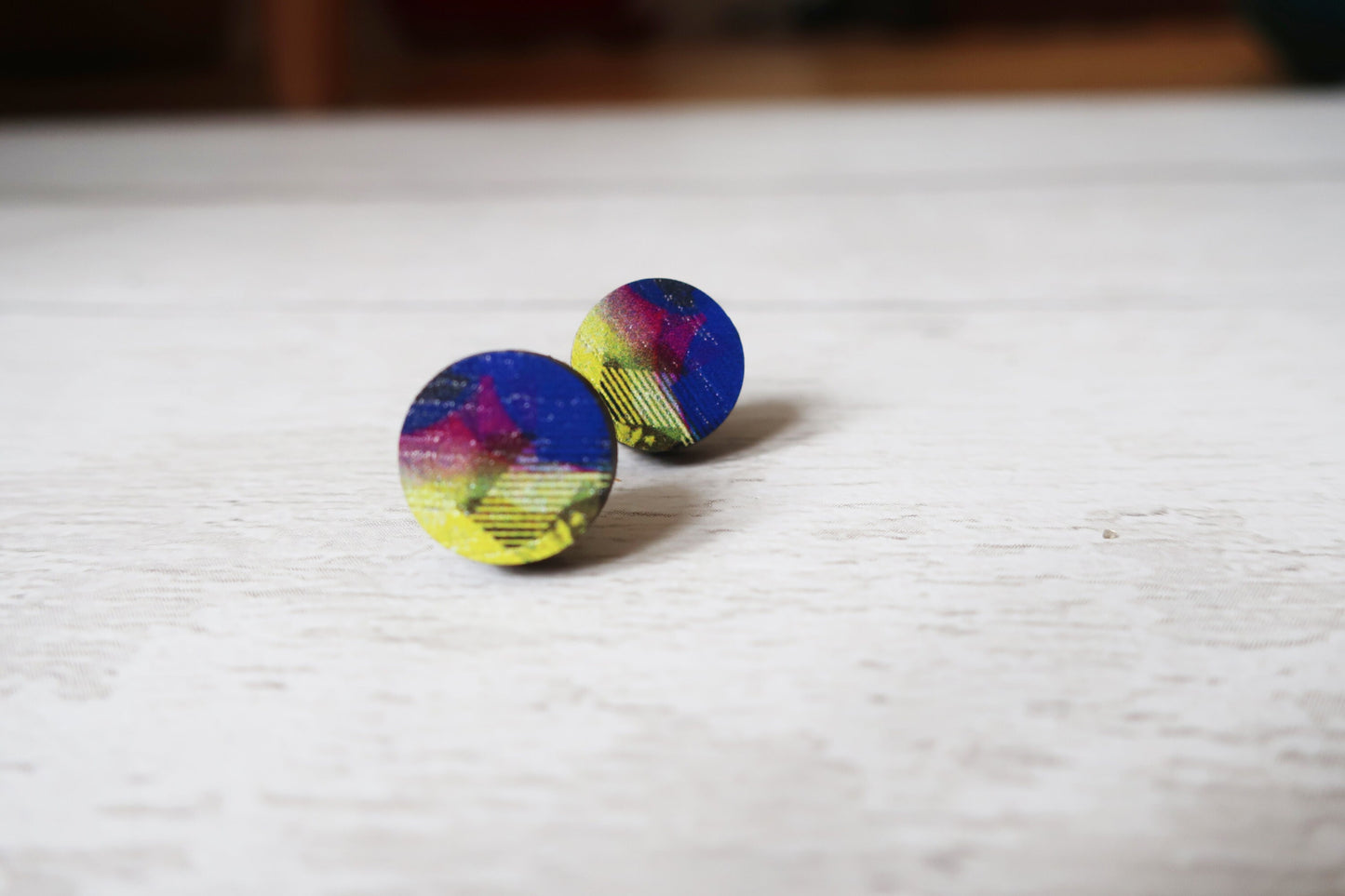 Colorful round earrings on a light wooden surface