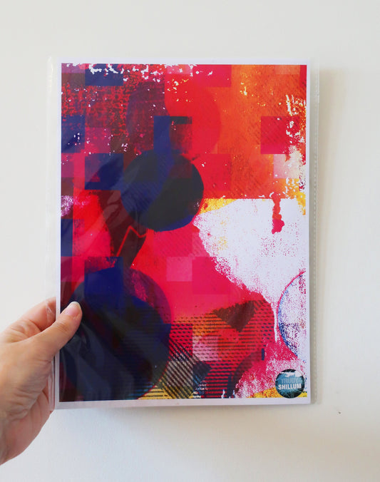 Colorful abstract art print held by a hand on a white background