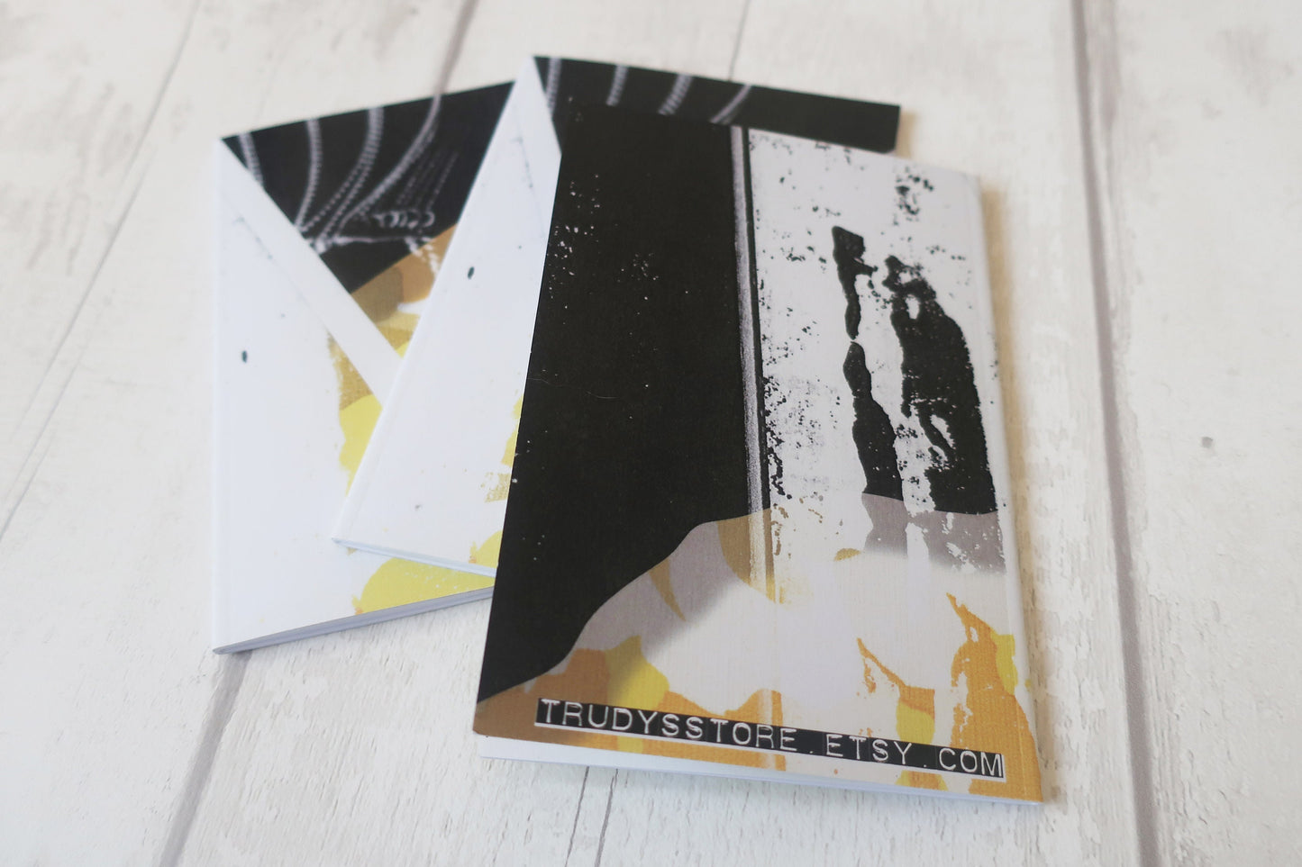Two black and white notebooks on a light wooden surface