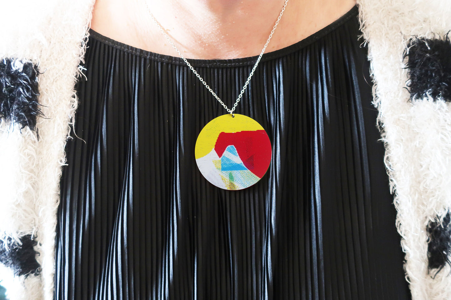 Person wearing a colorful pendant necklace with a black outfit