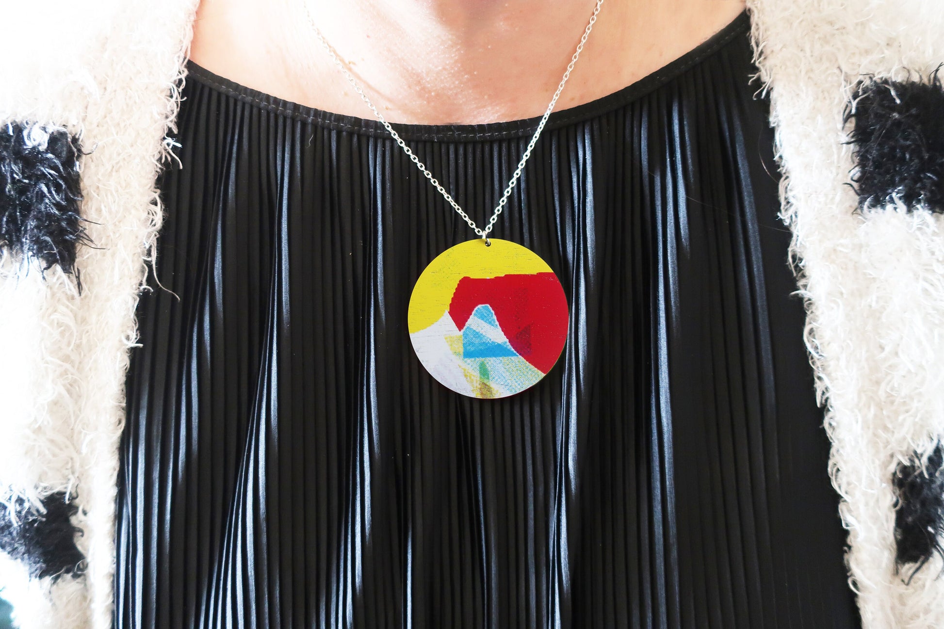 Person wearing a colorful pendant necklace with a black outfit