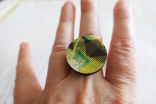 Hand wearing a ring with a green and black pattern on a white background