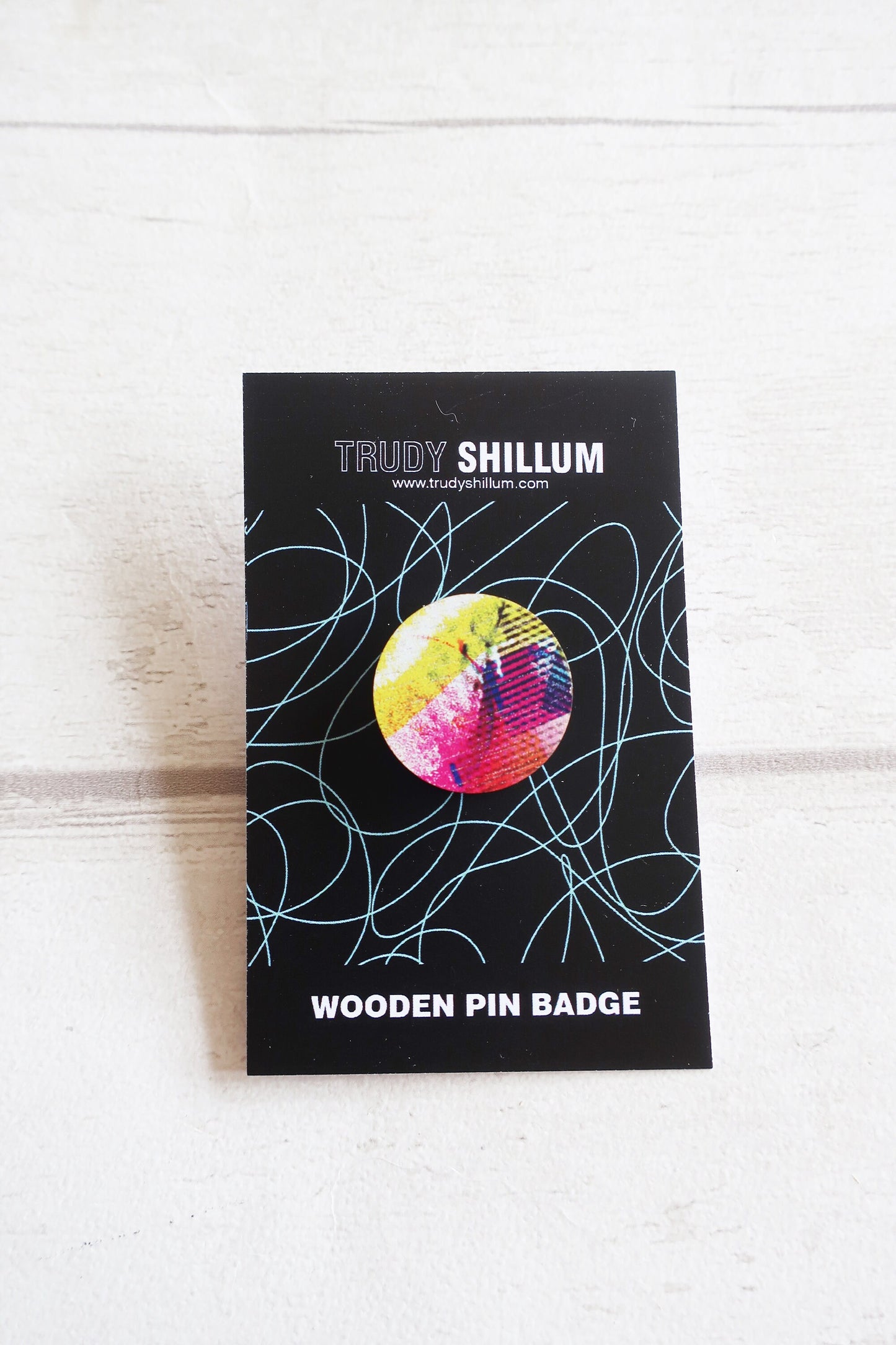 Trudy Shillum wooden pin badge packaging on a white wooden surface