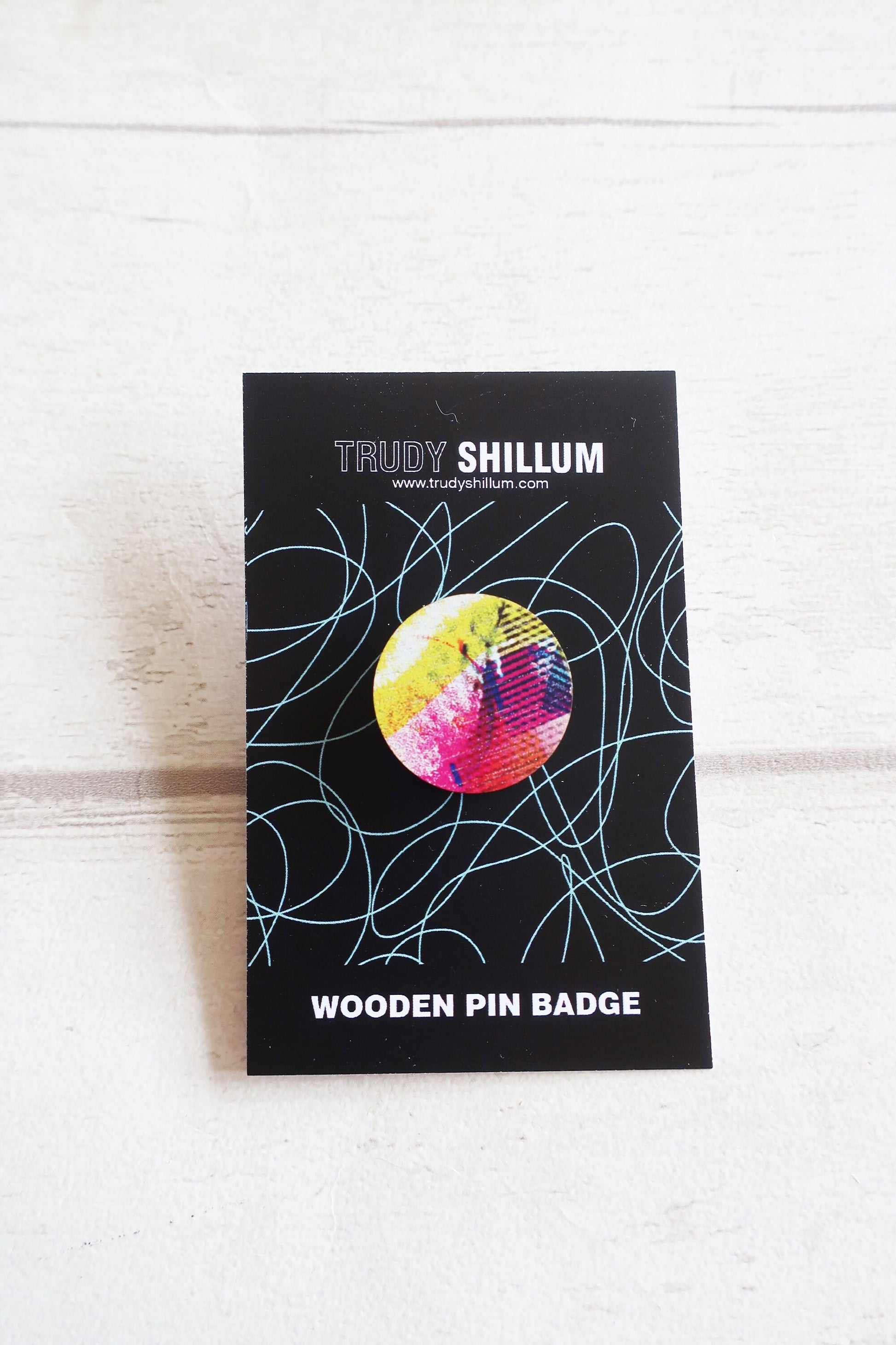 Trudy Shillum wooden pin badge packaging on a white wooden surface