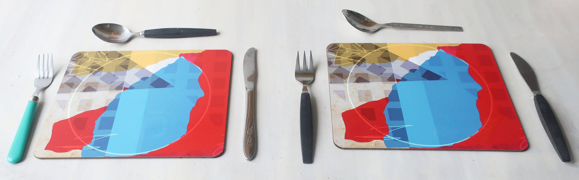 Colorful geometric placemats with cutlery on a white background