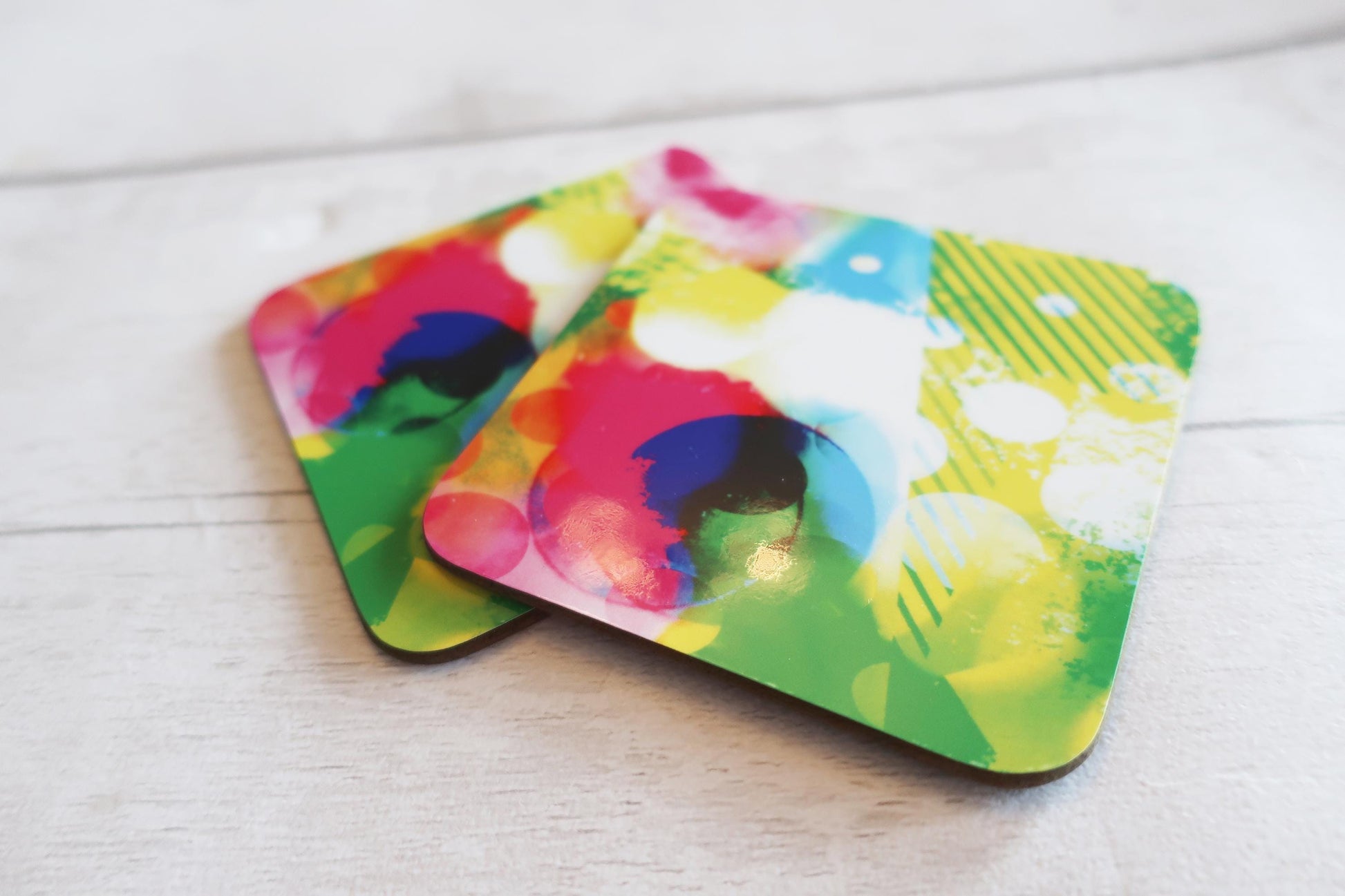 Colorful abstract design coasters on a light wooden surface