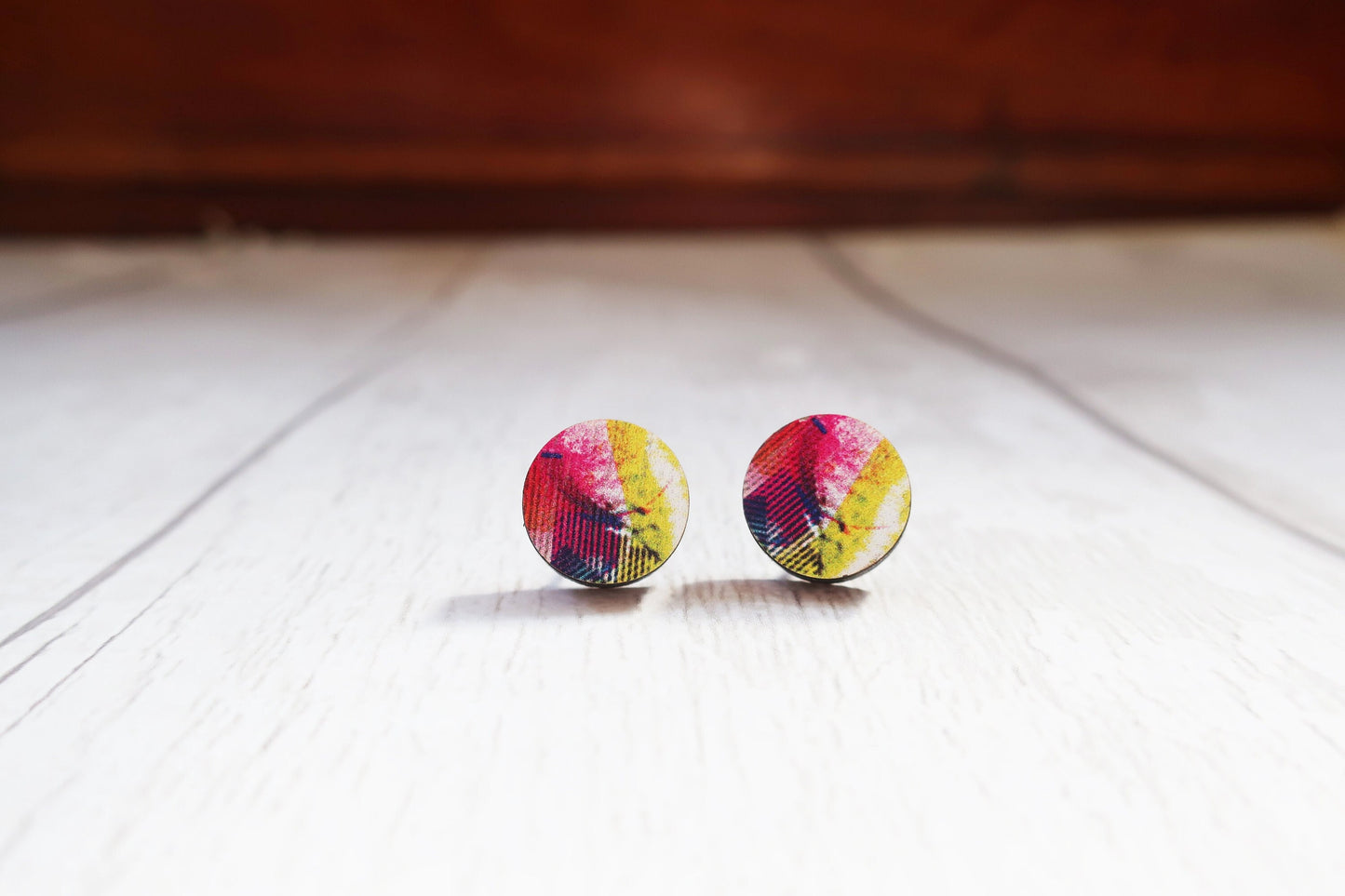 Colorful round earrings on a wooden surface