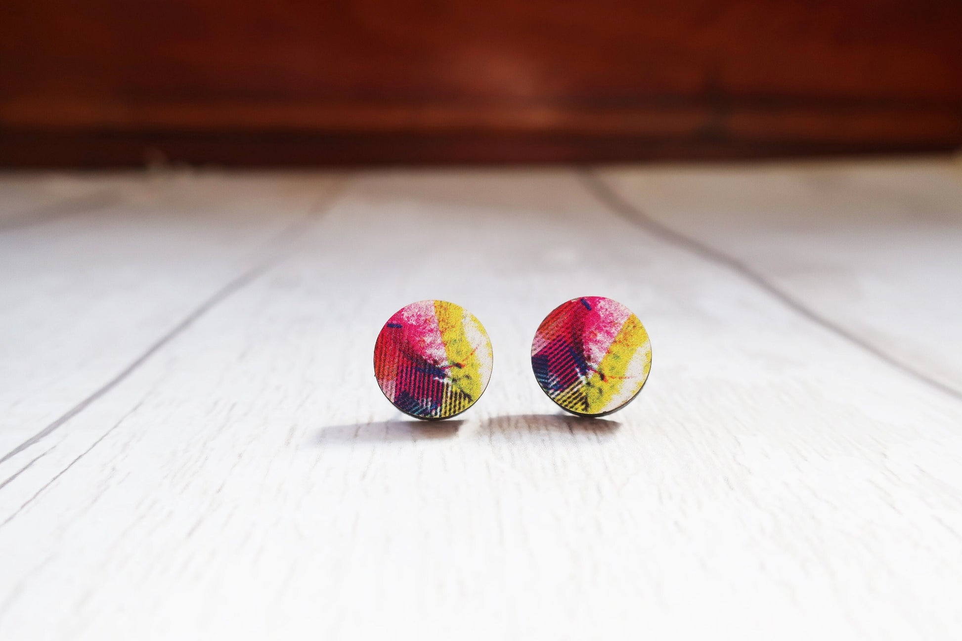 Colorful round earrings on a wooden surface