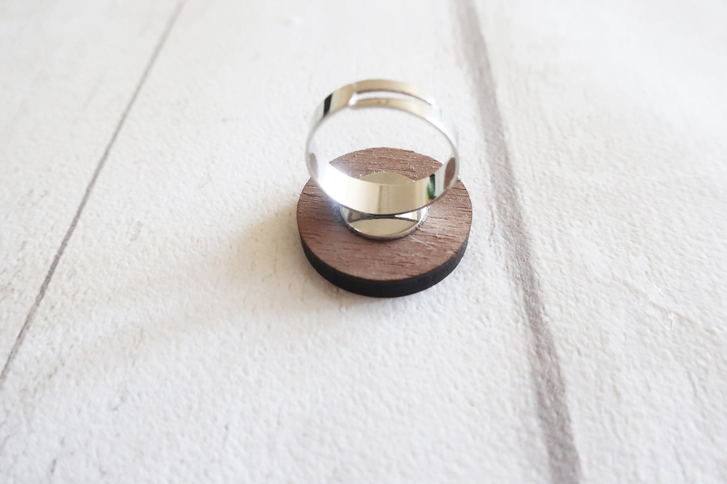 Silver ring on a wooden stand against a white background