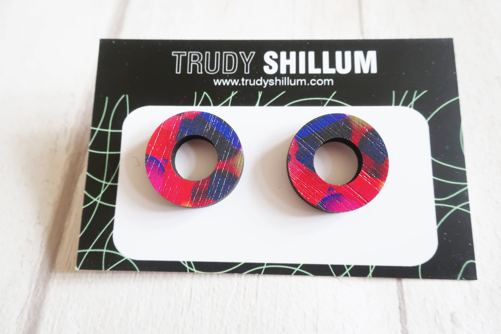 Colorful circular earrings on a Trudy Shillum branded card.