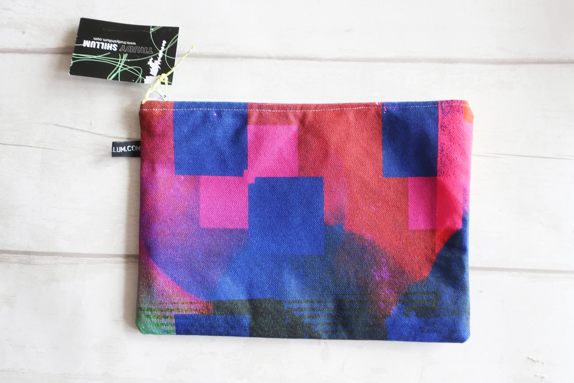 Colorful geometric-patterned pouch with a visible brand tag on a white wooden surface