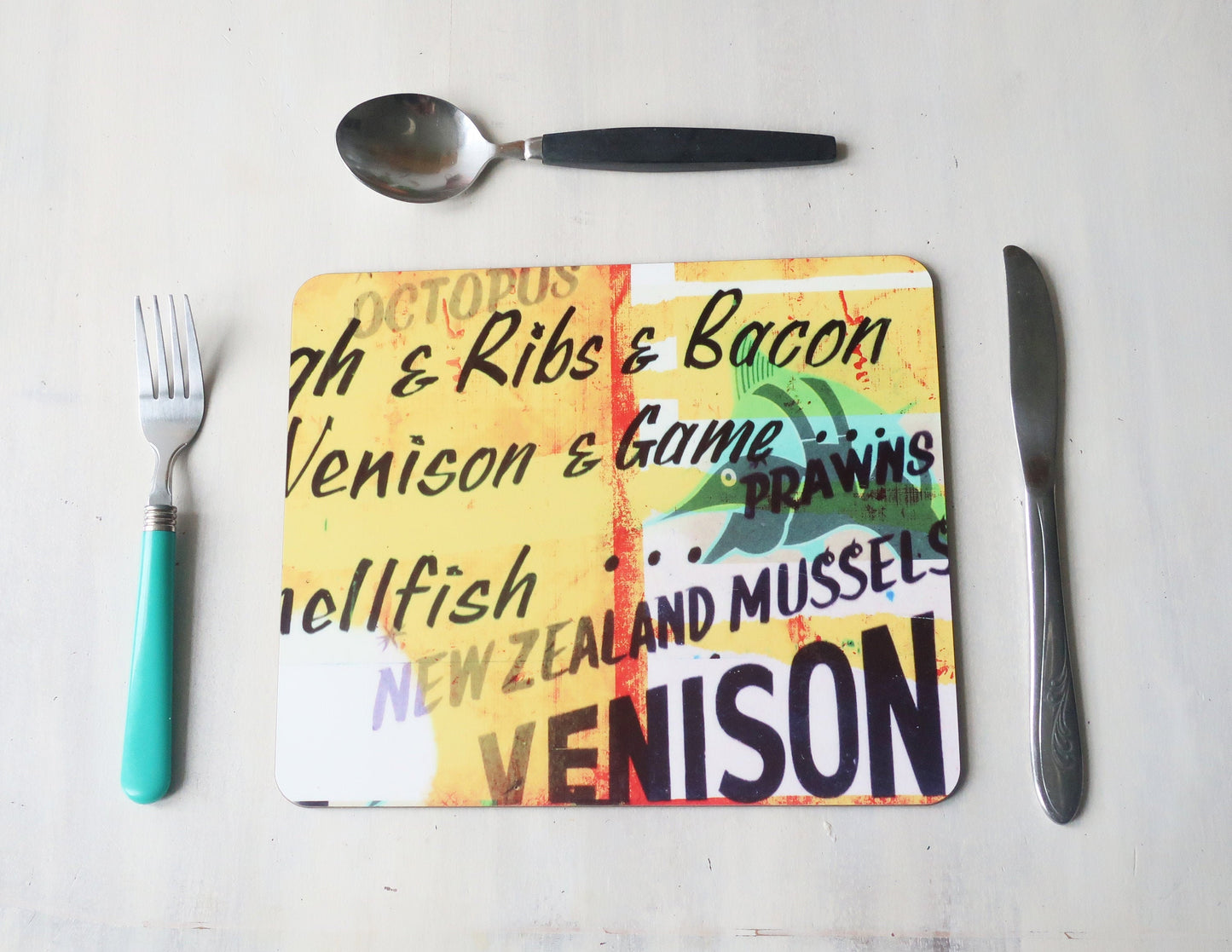 Colorful placemat  with text about food items on a white surface with utensils.