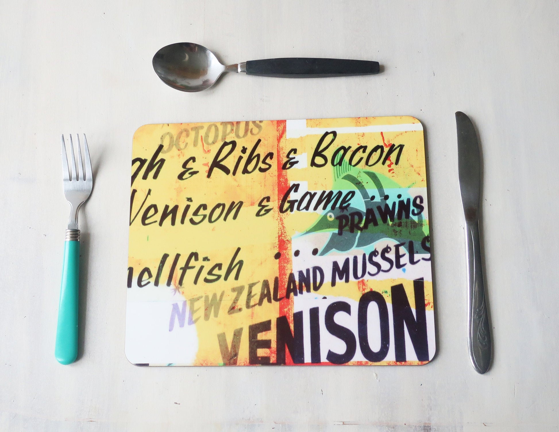 Colorful placemat  with text about food items on a white surface with utensils.