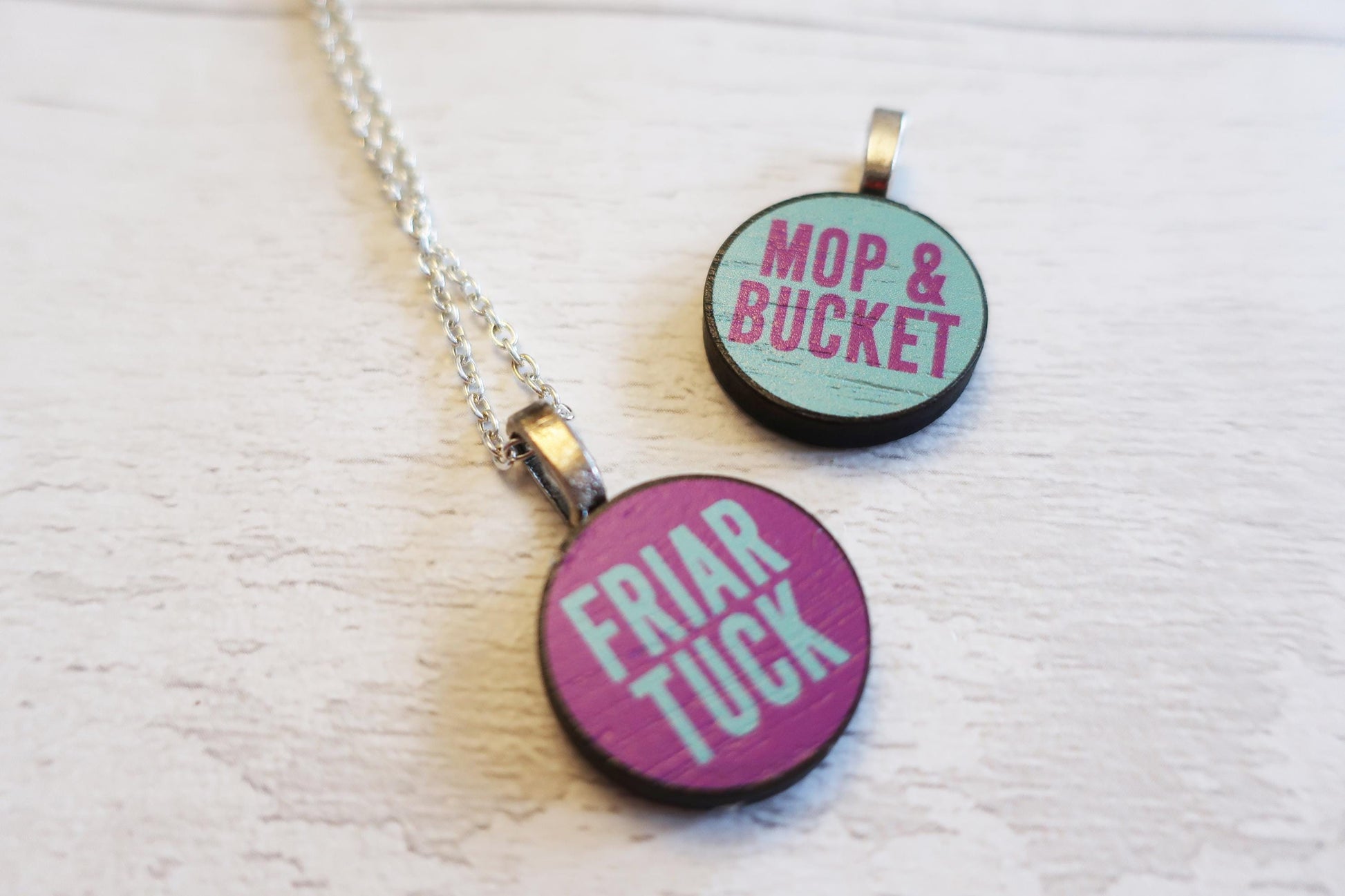 Two round pendants with 'Mop & Bucket' and 'Friar Tuck' text on a white background