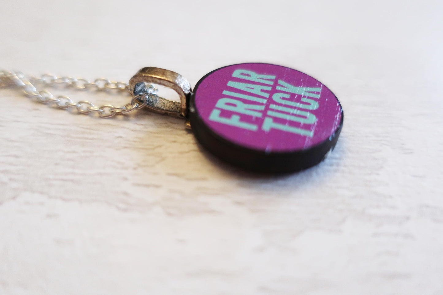 Necklace with a purple pendant displaying text on a white background