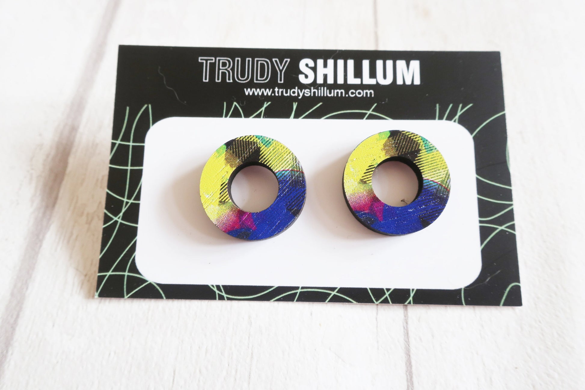 Colorful circular earrings on a Trudy Shillum branded card.